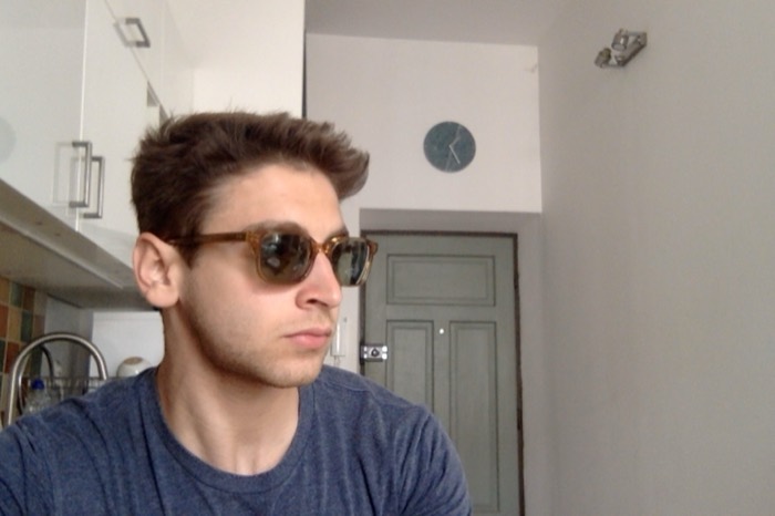 Joshua: webcam selfie in retro sunglasses, bright apartment kitchen