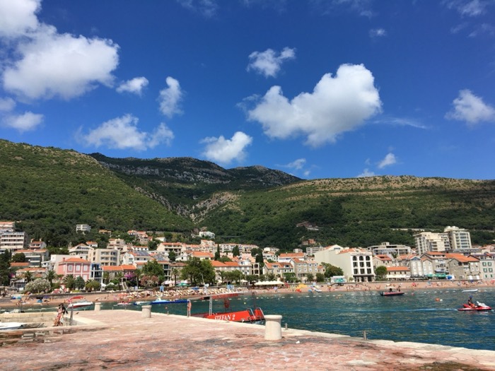 Petrovac beach town with mountains and red tour boat from pier