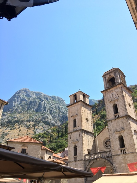 Kotor cathedral twin stone towers beneath dramatic mountain