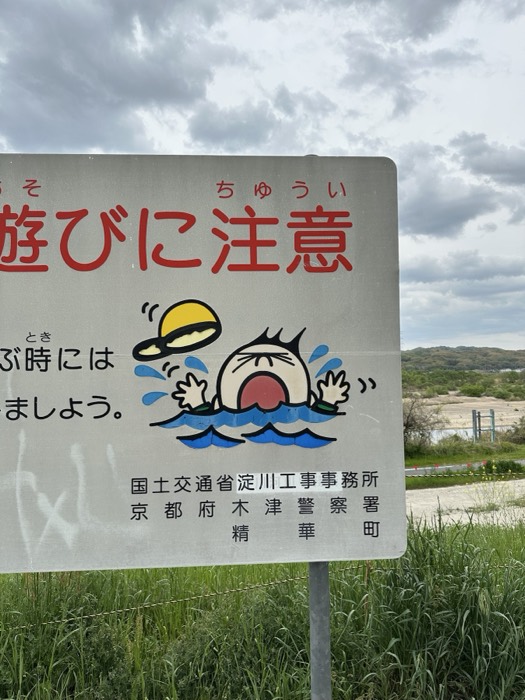 Quirky Japanese water-safety sign, drowning cartoon character by river