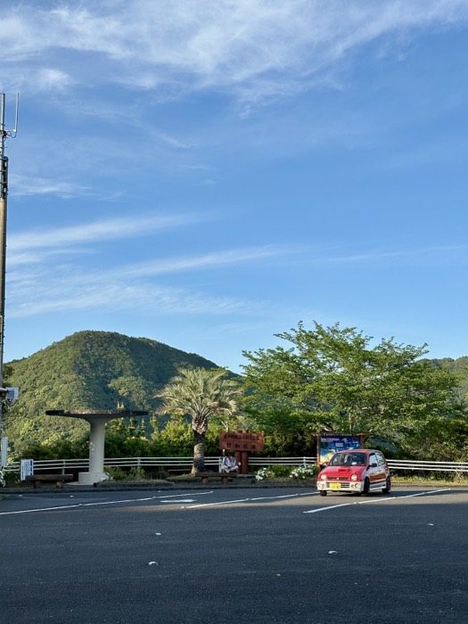 Roadside rest stop with little red kei car under big sky