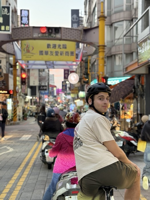 Joshua: on bike at dusk in busy Taiwanese market street