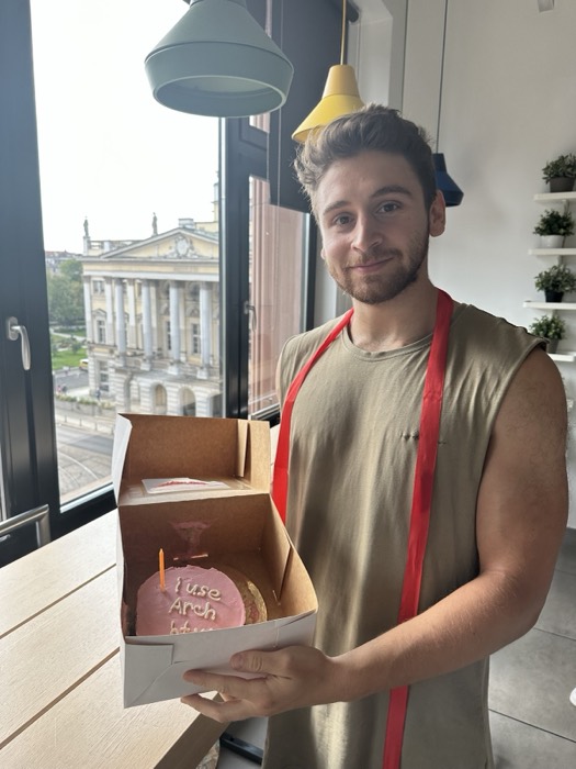 Joshua: holding I use Arch btw cake by opera window