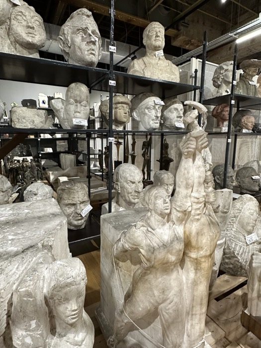 Caged towering plaster figure sculpture in industrial museum store