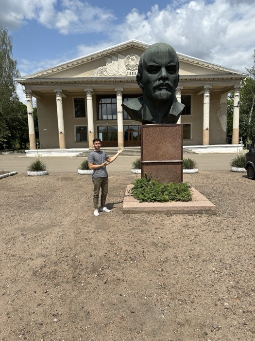 Joshua: posing arm-out beside enormous bronze Lenin head, columned palace