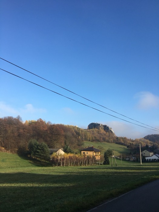 Autumn Jura landscape, white limestone crag above village, blue sky