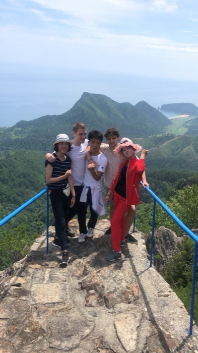 Joshua: group of friends on rocky cliff lookout, sea view