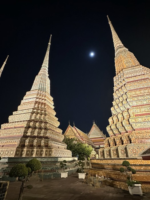 Wat Pho jewelled chedi spires lit up against night sky