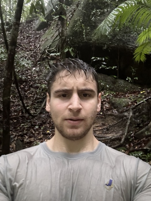 Joshua: sweaty jungle selfie, wet hair, mid-hike against rocks