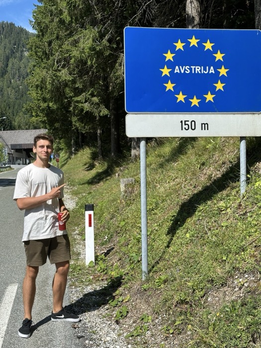 Joshua: pointing at AVSTRIJA EU border sign, Slovenia-Austria crossing