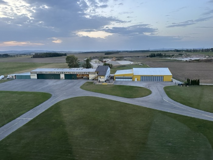 Aerial of Flugplatz Stockerau, hangars and runway, pink dusk sky