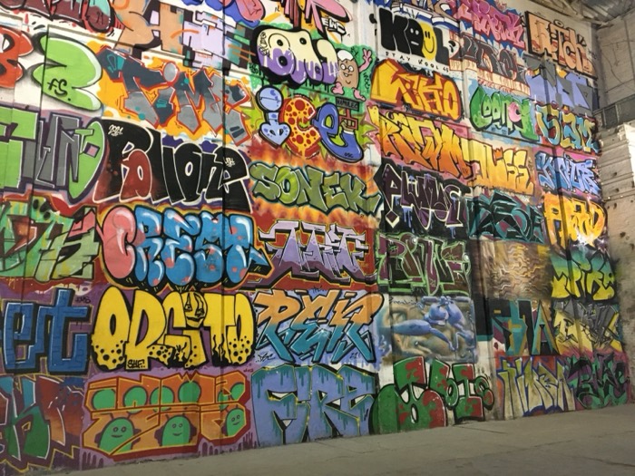 Dense colorful graffiti-covered wall in industrial space