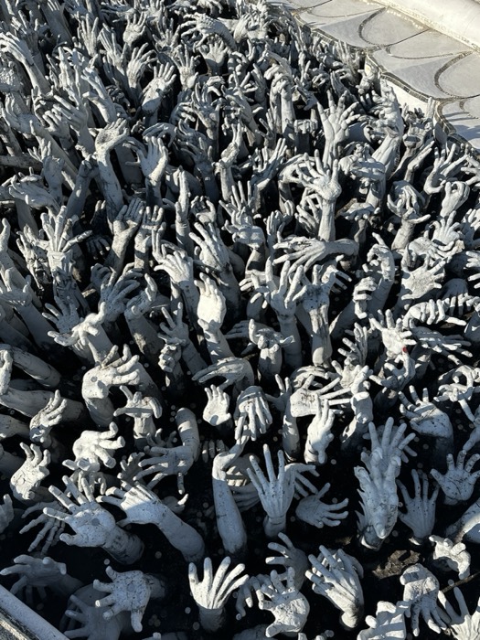 Field of reaching hand sculptures at White Temple