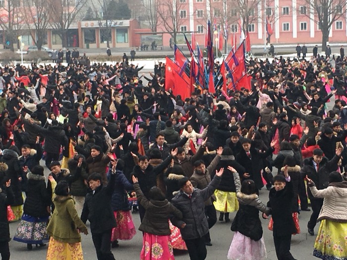 Mass synchronized dance with flags in city square, striking North Korean spectacle