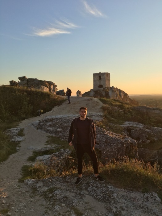 Joshua: standing on rocky hilltop below Olsztyn castle ruins at sunset