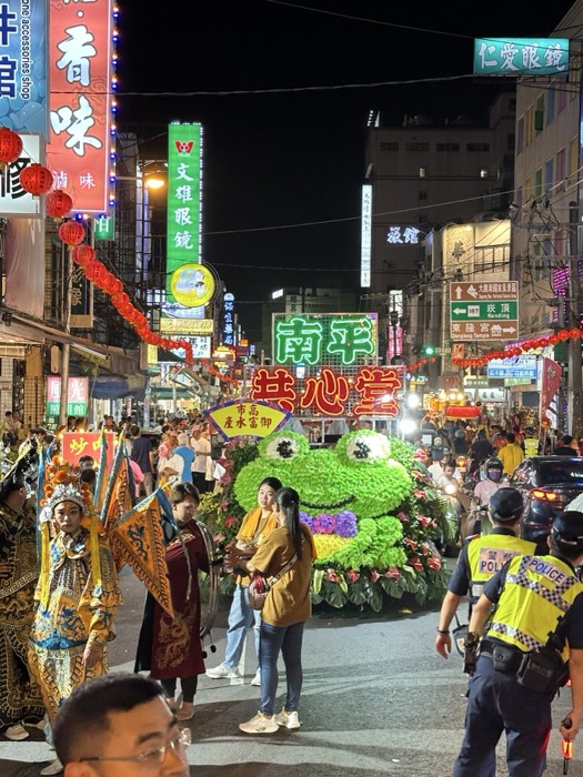 Night temple parade with giant flower frog float, crowd