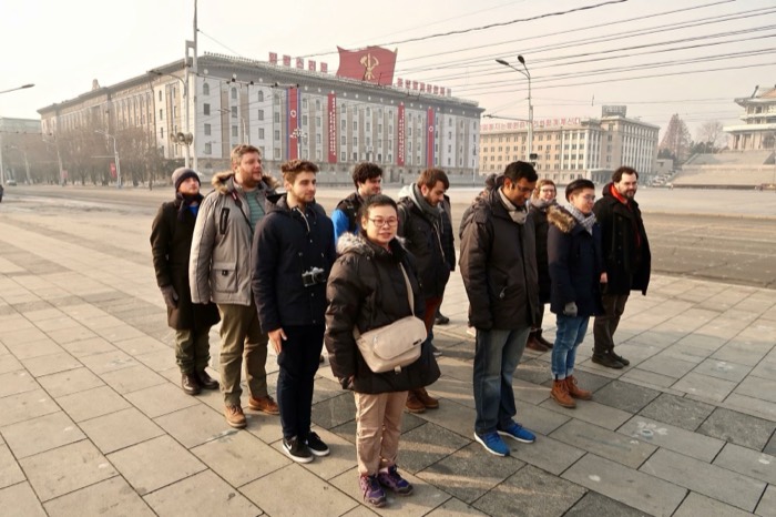Joshua: with tour group at Kim Il Sung Square, propaganda banners on ministry building