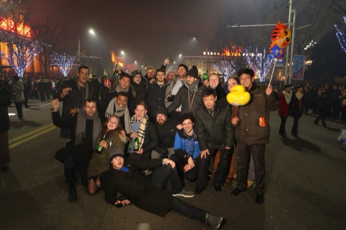Joshua: jubilant tour group on NYE street with neon trees, balloons and NK flags