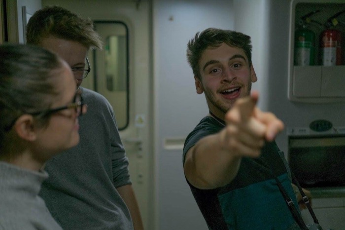 Joshua: grinning and pointing at camera on train, North Korea