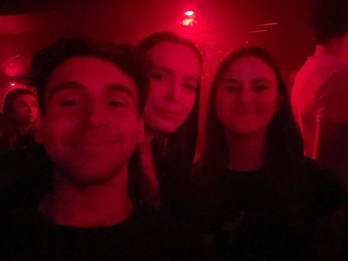 Joshua: dim red-lit club selfie with two female friends