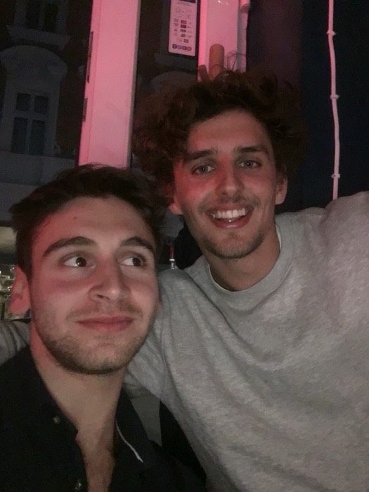 Joshua: selfie with friend under pink neon, night out.