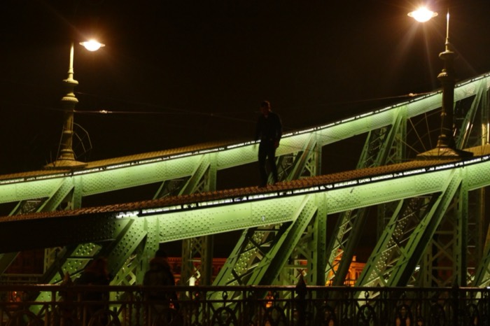 Joshua: silhouetted on green Liberty Bridge girders at night