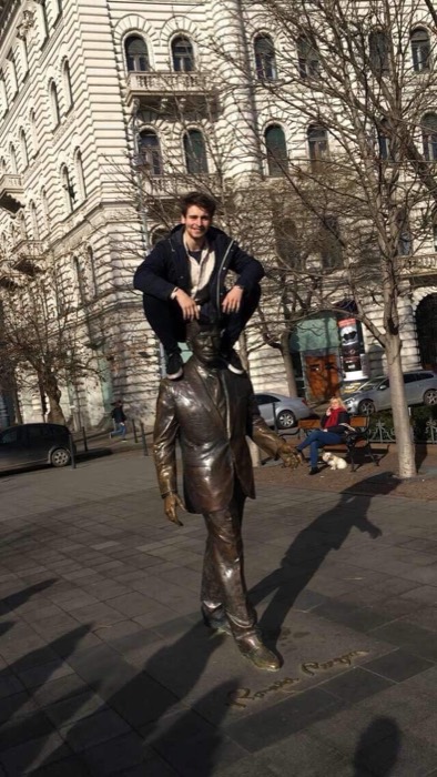 Joshua: sitting on shoulders of bronze statue, sunny street