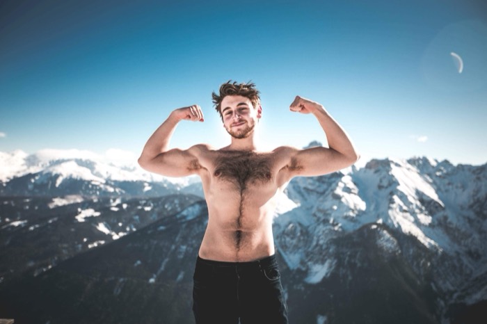 Joshua: shirtless flexing on snowy Alpine summit, bright sky