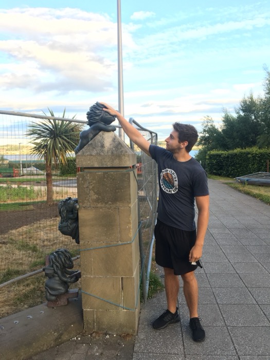 Joshua: reaching up to playful lion statues by waterfront