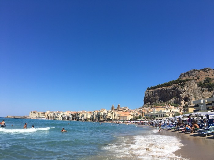 Cefalu old town and headland behind crowded beach and sea
