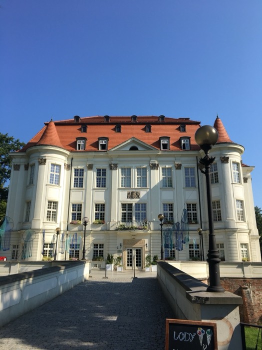Lesnica Castle white baroque facade with red roof under blue sky