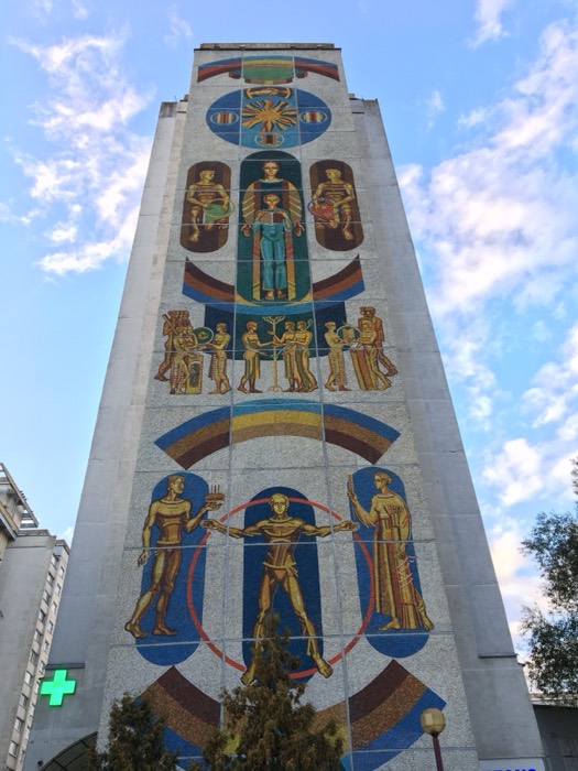Towering Soviet-era mosaic mural of figures and rainbows on building, Minsk