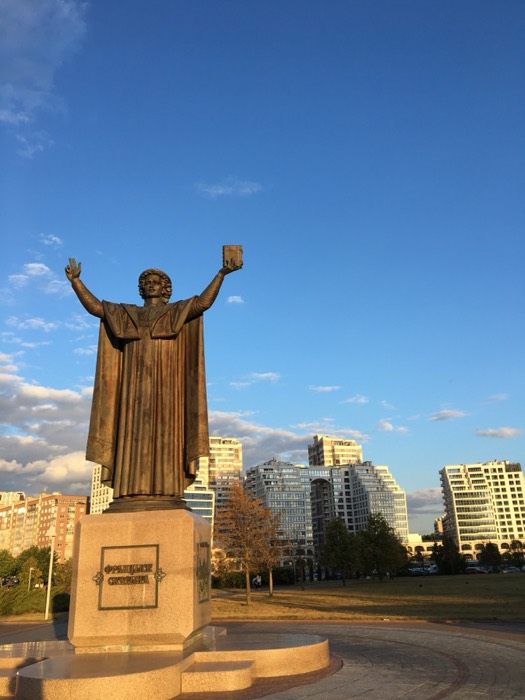 Bronze Francysk Skaryna statue against modern Minsk skyline, golden light