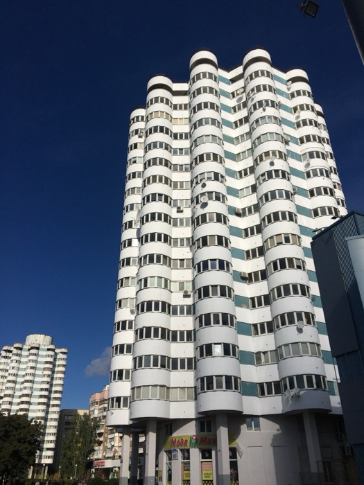 Sculptural curved white Soviet-modernist apartment towers against blue sky, Minsk