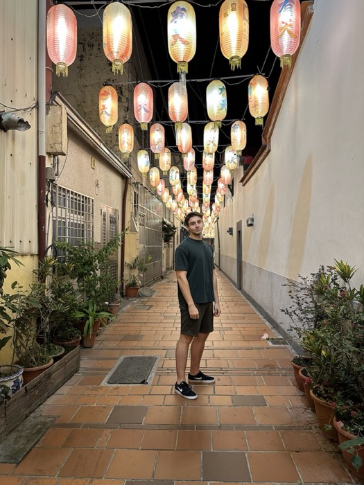 Joshua: standing in narrow alley under glowing painted paper lanterns