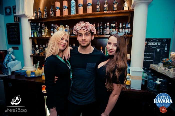 Joshua: in flower crown posing with two women at Havana hostel bar