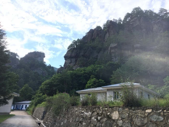 Dramatic rocky crags rising above village houses, blue sky