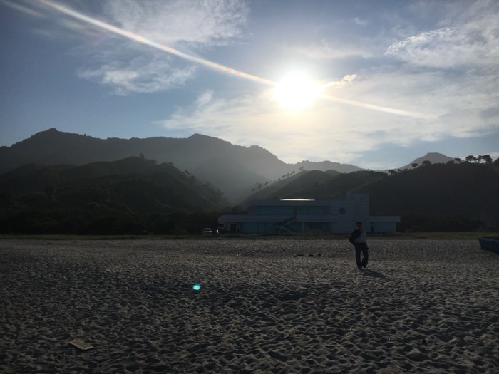 Misty mountains over beach, lone figure, modernist seaside building
