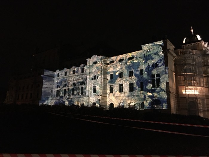 Historic building facade lit by colourful light projection at night