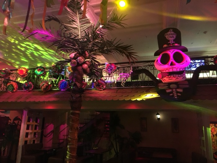 Neon-lit Cuban bar with skull mask, palm and Havana Club