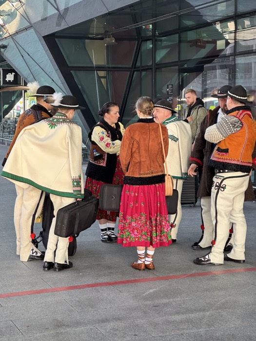 Polish Goral highlanders in folk costume outside modern glass building