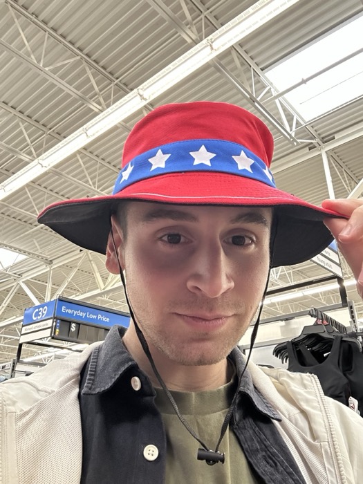 Joshua: selfie trying on stars-and-stripes bucket hat in Walmart