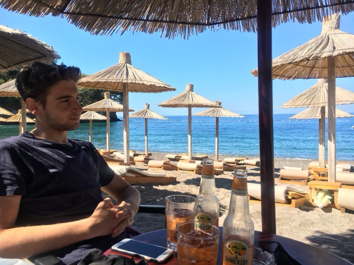 Friend at beach bar with thatched umbrellas, sea, Somersby ciders