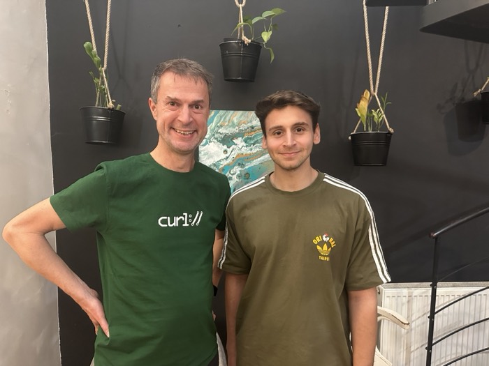 Joshua: with curl creator at conference, plants on wall behind