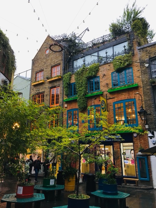 Colorful Neal's Yard courtyard, ivy-clad brick facades and string lights