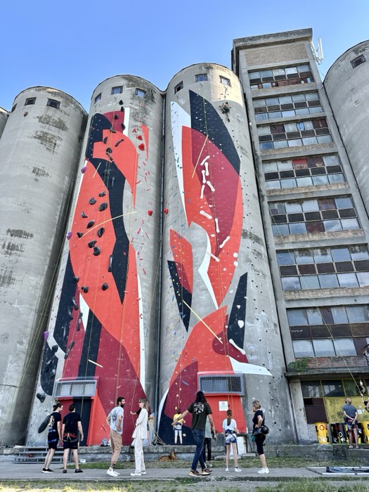 Climbing wall mural on abandoned grain silos with climbers below