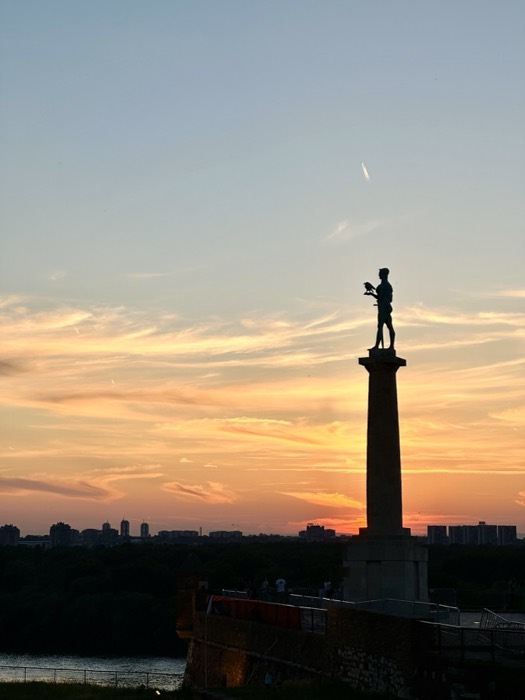 Victor monument silhouette against vivid orange sunset over Danube