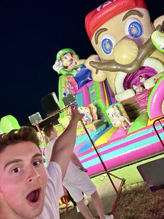 Joshua: shocked-face selfie at festival, giant inflatable Mario bouncy castle