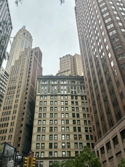 Look-up at ornate beaux-arts skyscraper between Manhattan towers.