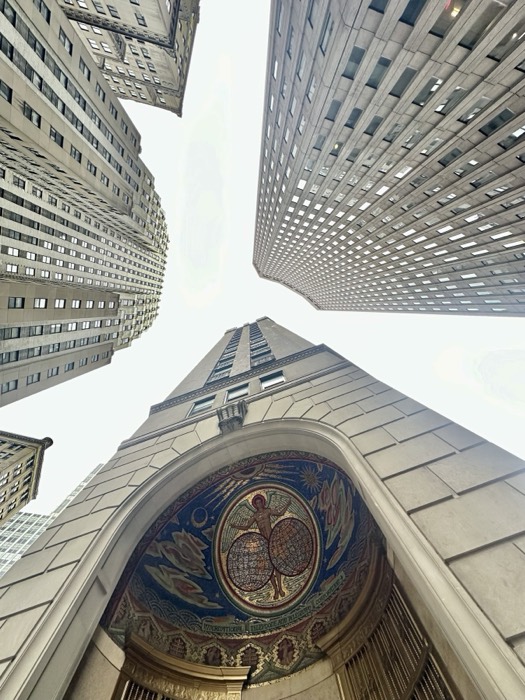 Look-up at golden mosaic archway framed by converging Manhattan skyscrapers